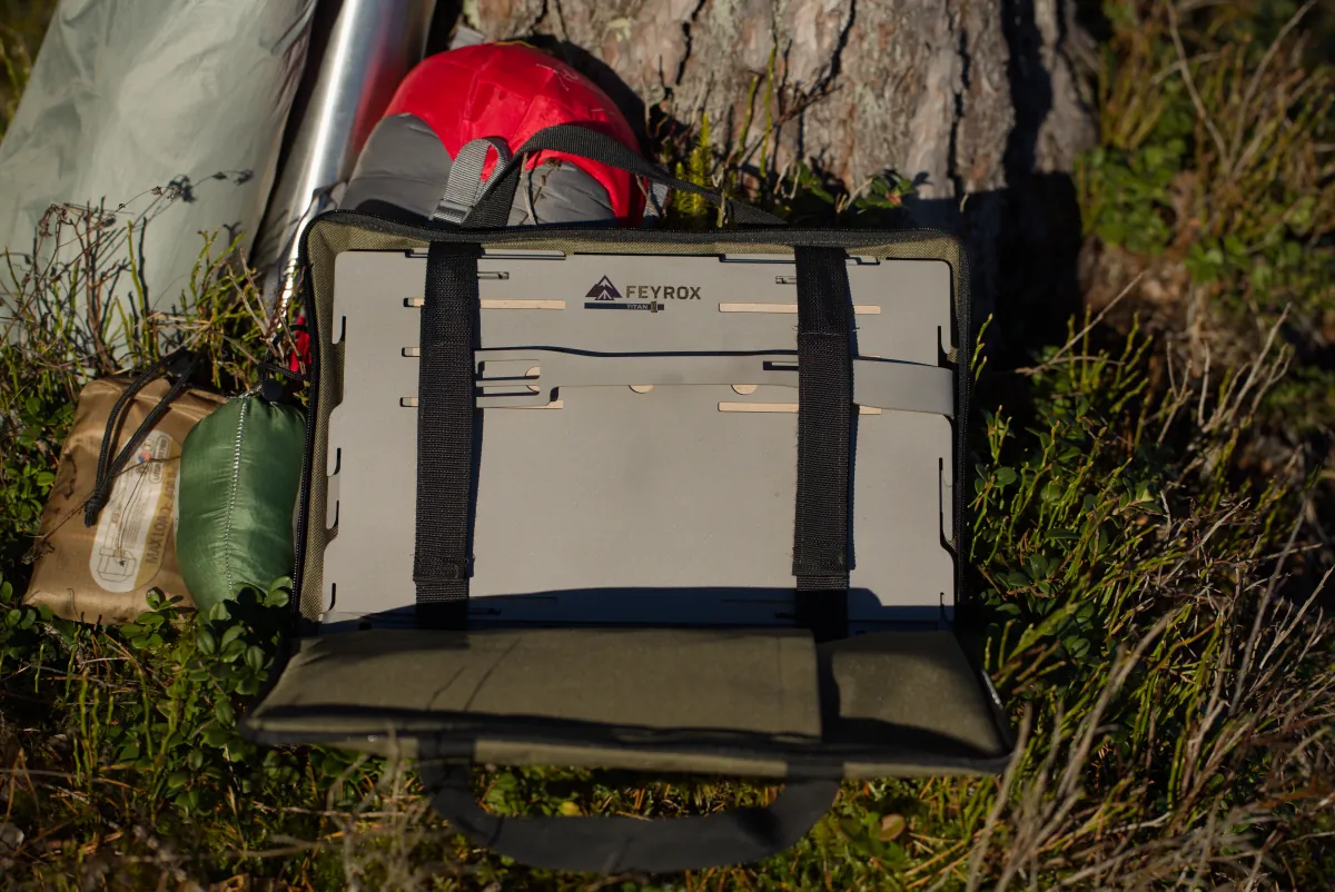 Titan1 packed flat inside its carry bag, leaning against a tree at camp