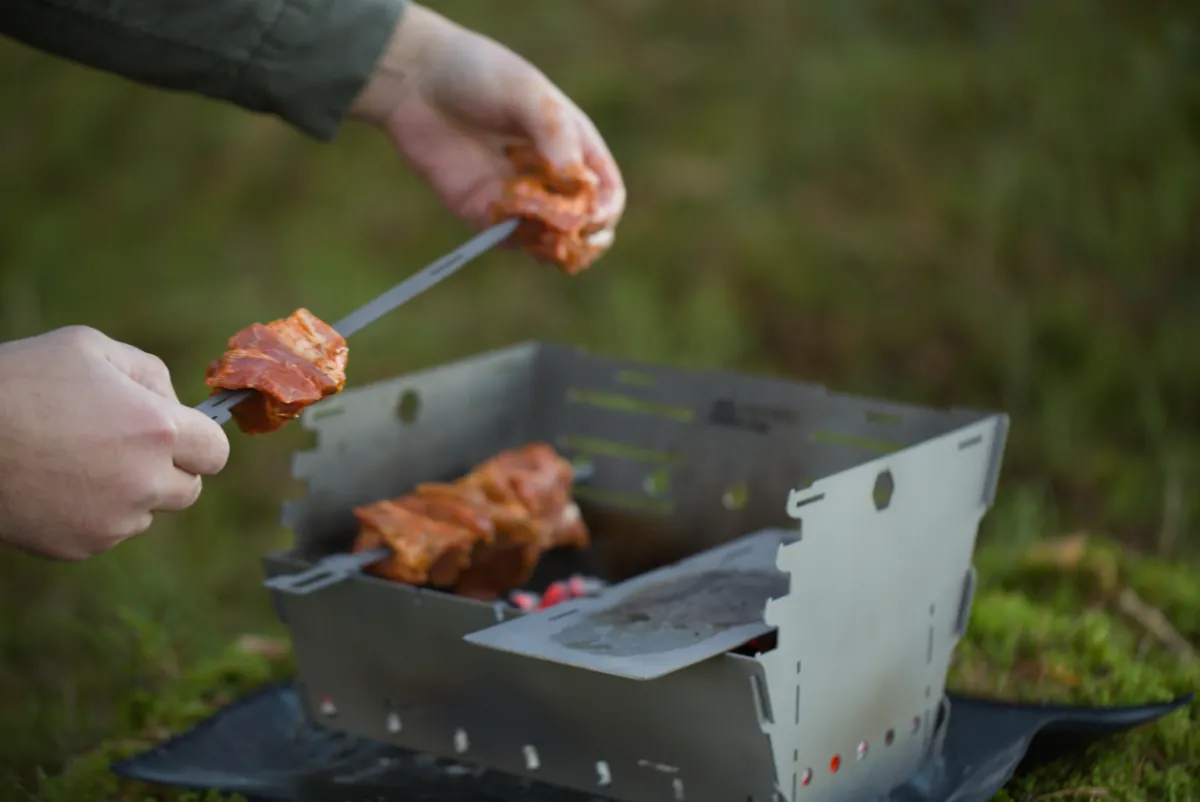Loading meat onto a long-handled titanium skewer over the Titan1